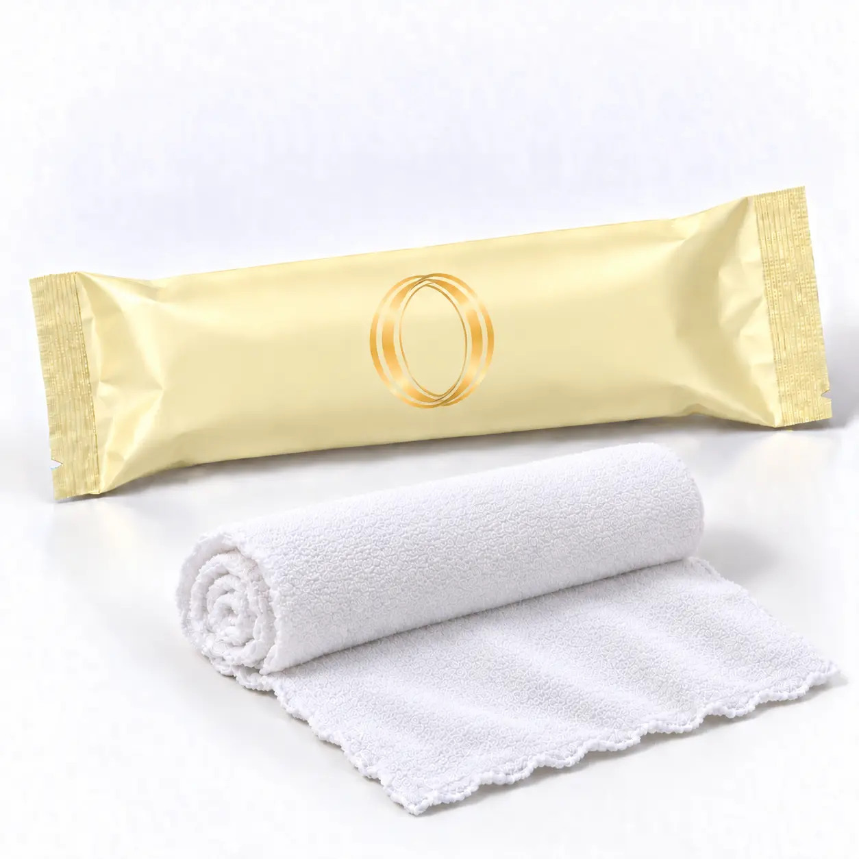 Lemon oshibori towel in pale yellow packaging laid flat beside the rolled white microfiber towel